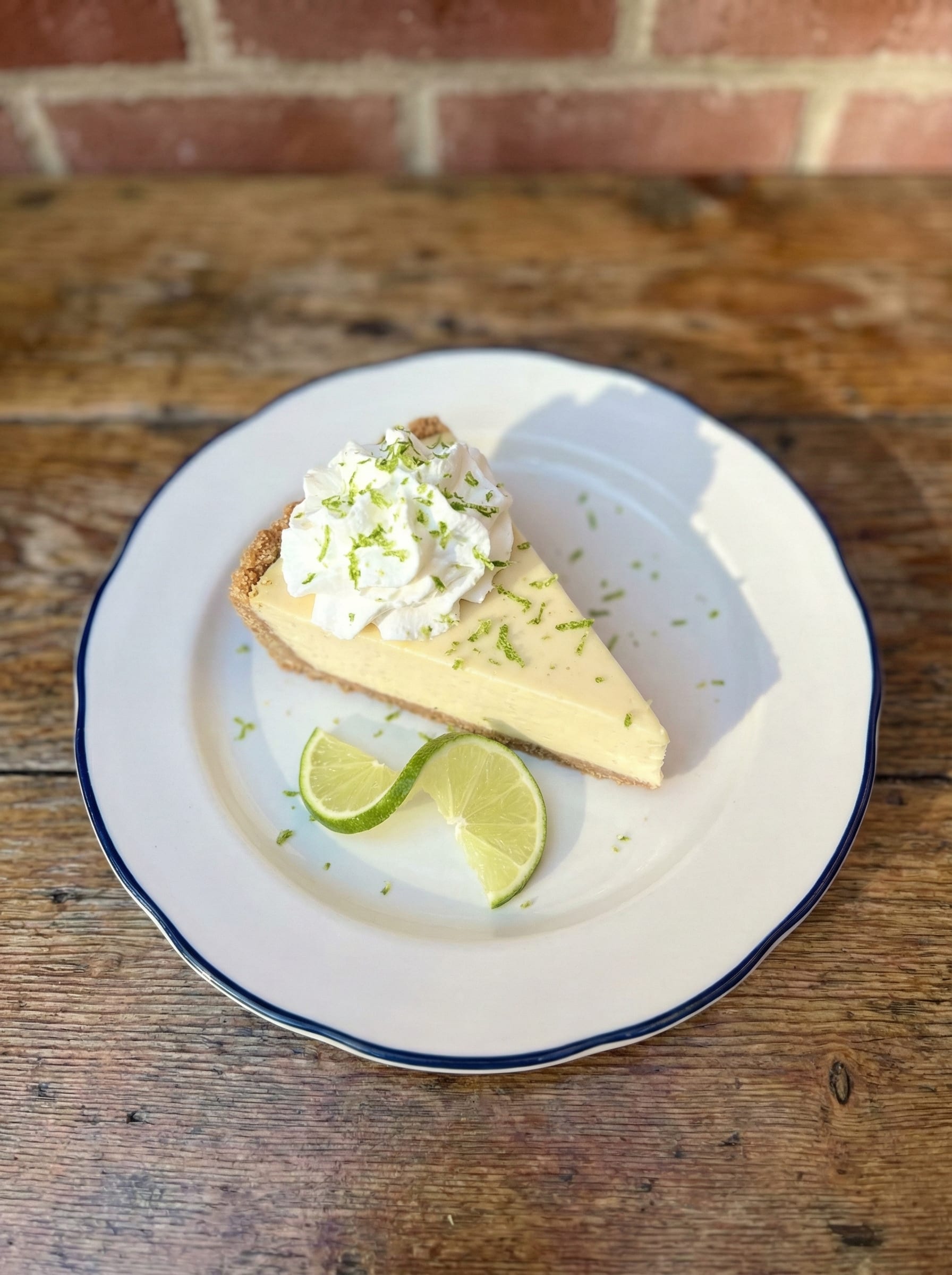Slice of key lime pie topped with whipped cream and lime zest